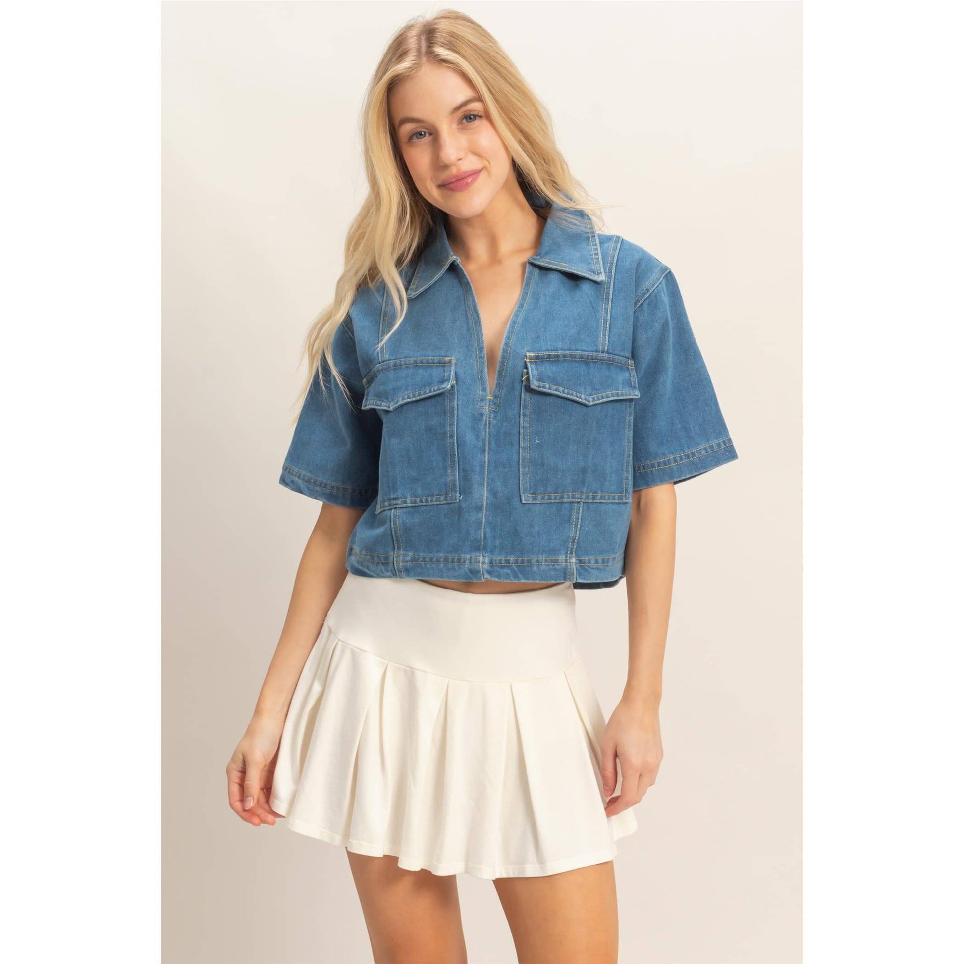 Woman wearing a blue denim jacket and white skirt on a beige background