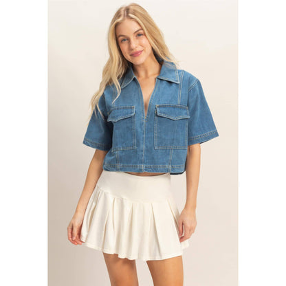 Woman wearing a blue denim jacket and white skirt on a beige background